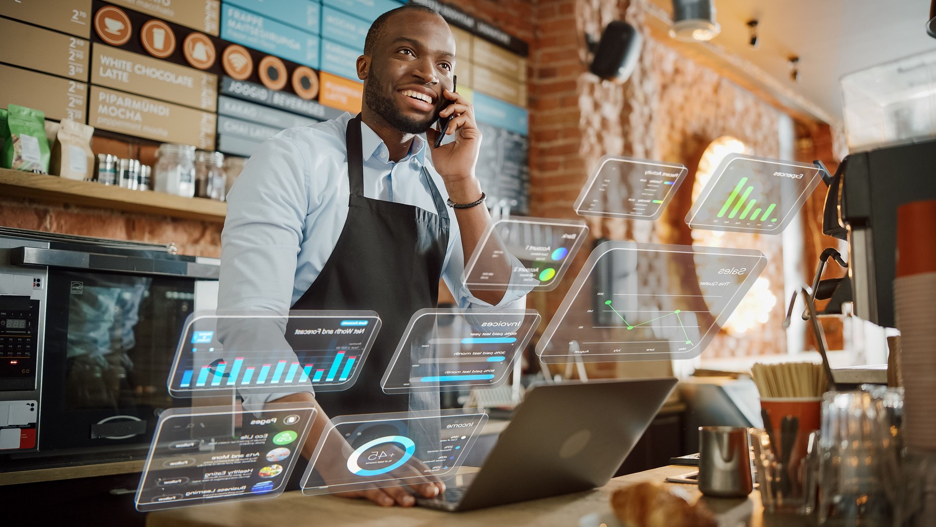 African American Coffee Shop Owner is Working on Computer and Talking on a Phone in a Cute Cafe. Augmented Reality Icons Popping Out of Restaurant Manager's Laptop: Small Black Business Concept.